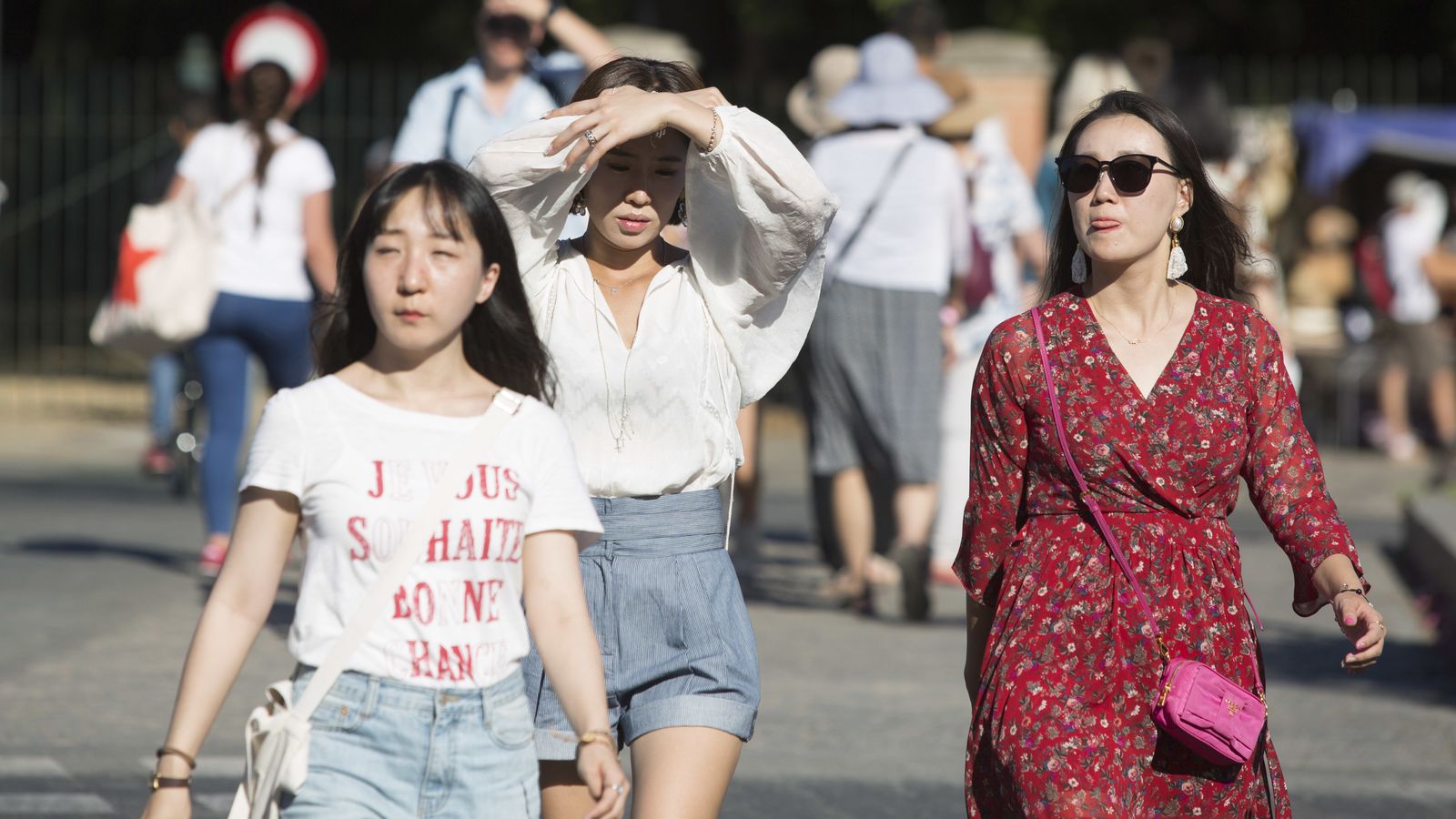 Tres turistas pasean por una calle de Sevilla.