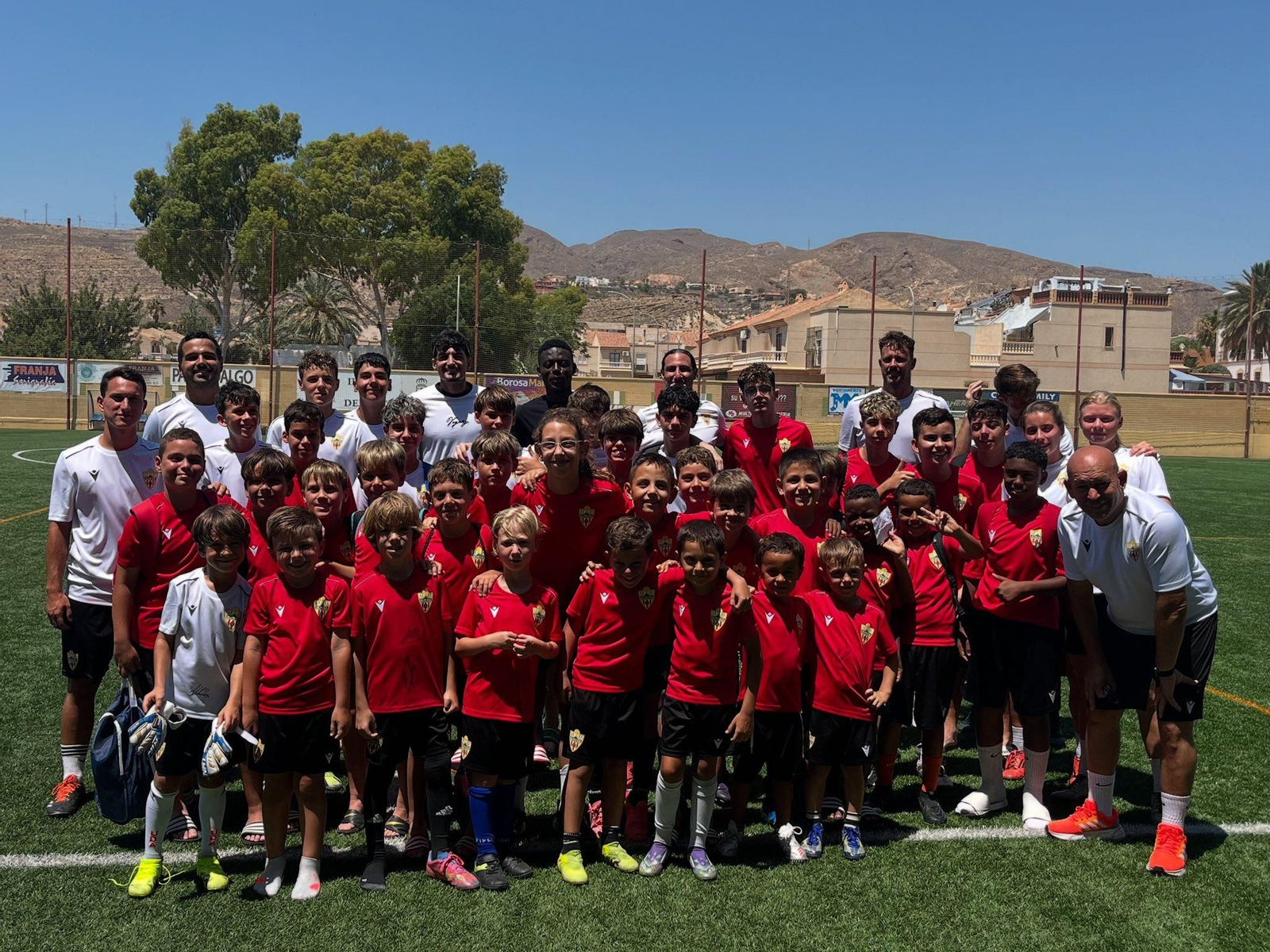 Los participantes del campus de la UD Almería posan junto a los futbolistas del primer equipo Idrissu Baba y Álex Muñoz.