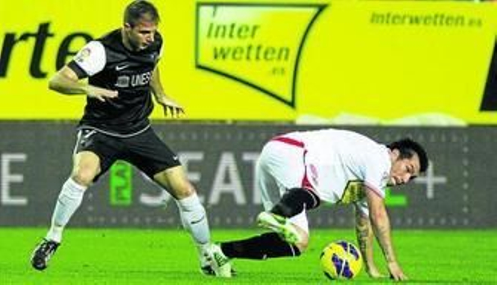 Medel protege el balón cayéndose al suelo ante Joaquín.