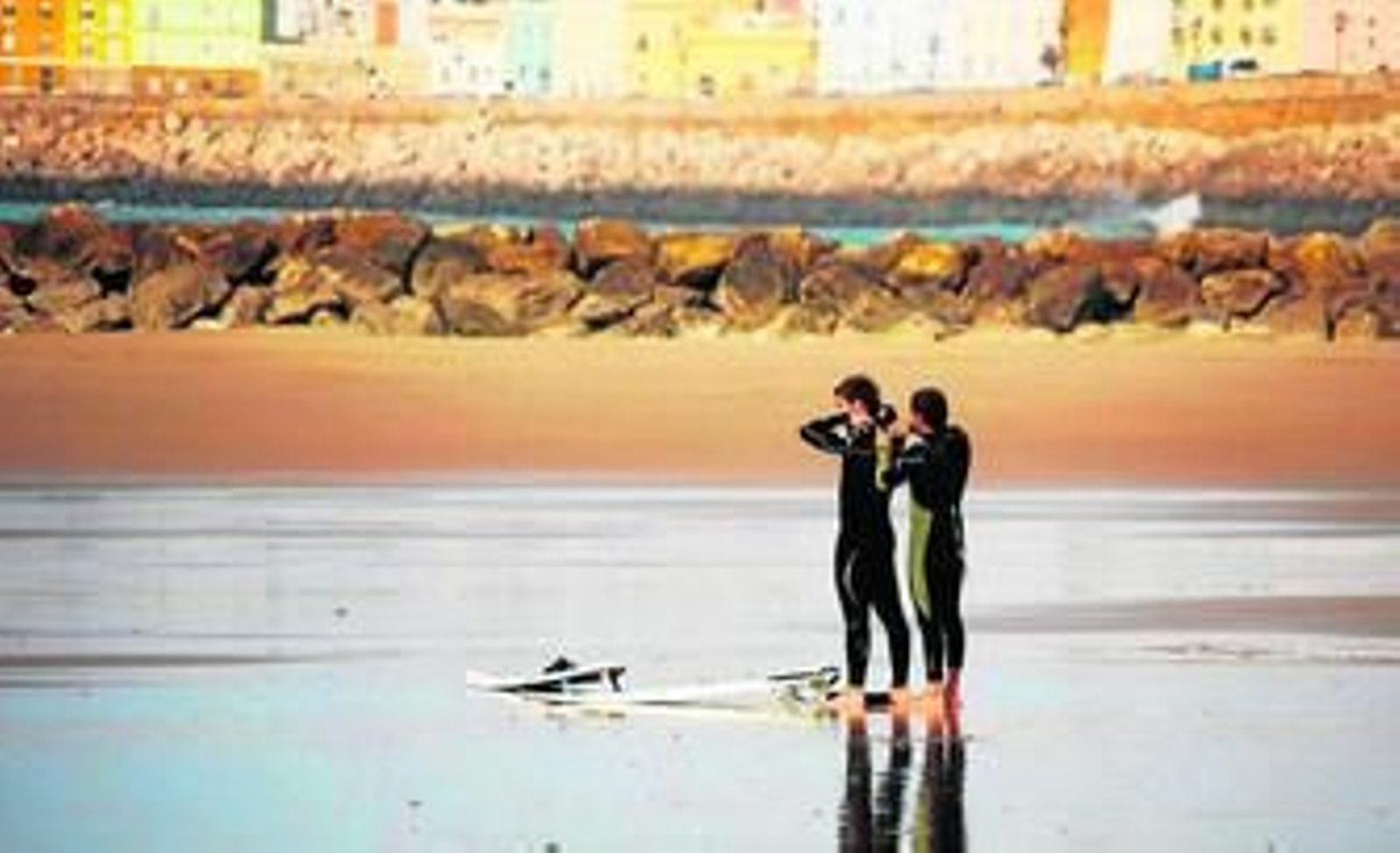 Dos jóvenes surfistas se preparan antes de entrar al agua en la playa de Santa María del Mar.