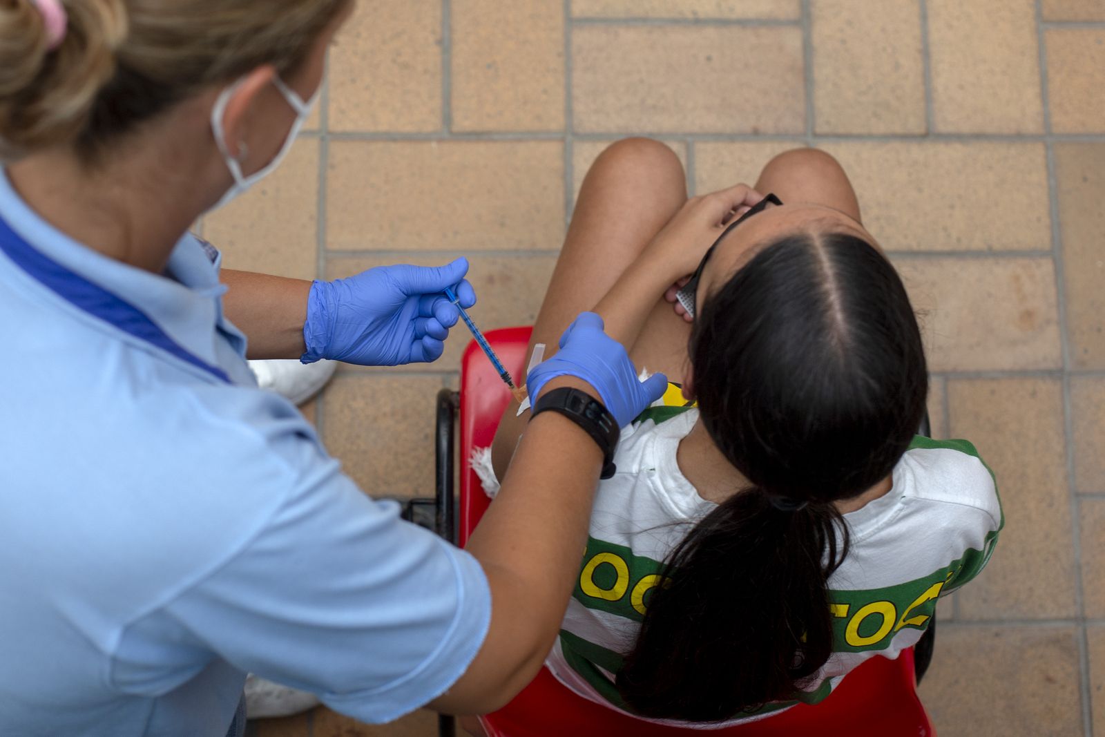 Una enfermera pone una vacuna a una joven.