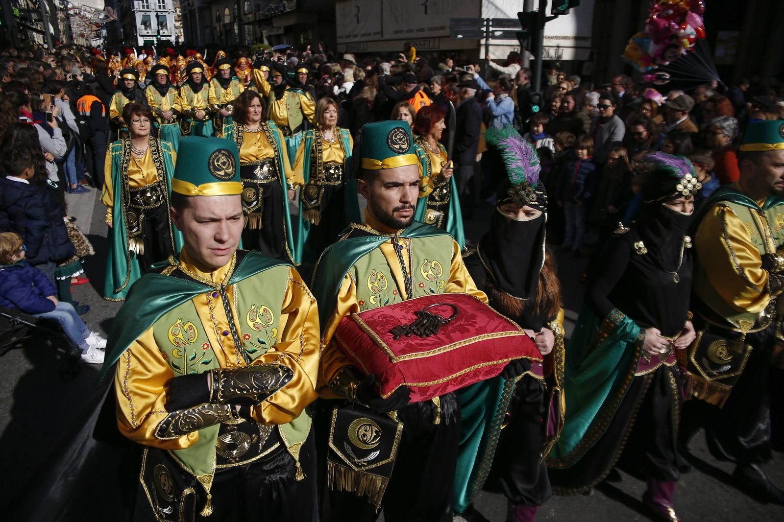 1. La concejal popular María Francés fue la encargada de tremolar el Estandarte en el balcón del Ayuntamiento. 2 y 3. El desfile de Moros y Cristianos llenó de color las calles de la capital. 4. La comitiva pasó por delante de la estatua de Isabel La Católica. 5. La presencia  de colectivos en contra de la Toma  fue este año más minoritaria.