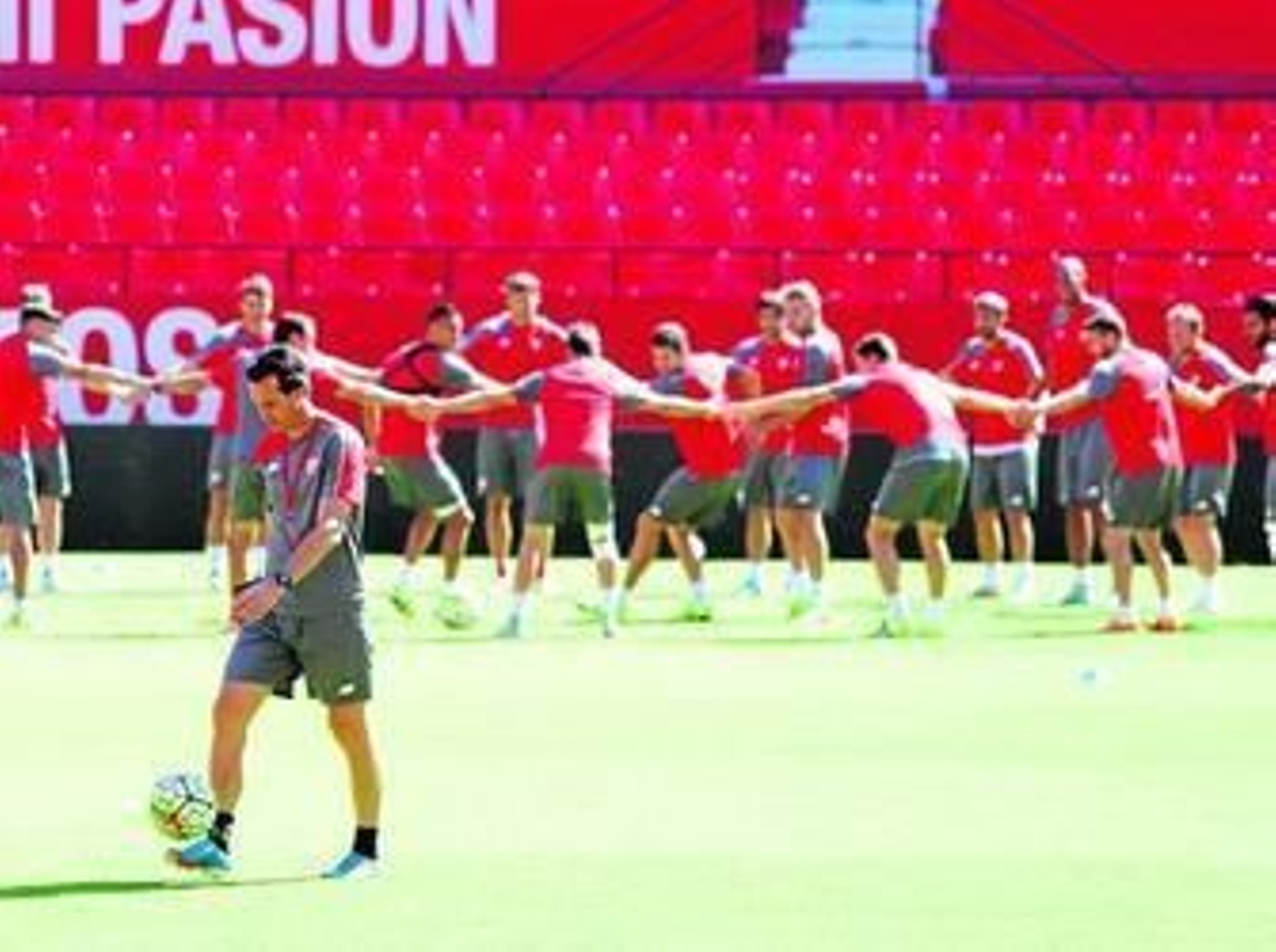 Unai Emery, con la plantilla cogida de las manos al fondo.