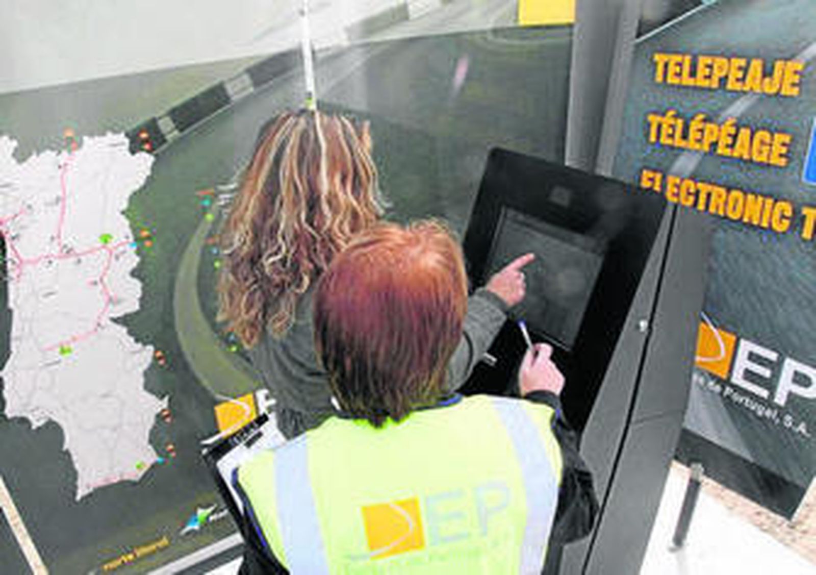 Una usuaria utiliza el sistema de cobro del peaje junto a una empleada de autopistas de Portugal.