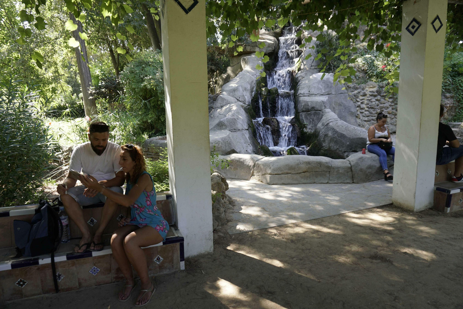 Turistas junto a la cascada de agua del monte Gurugú del parque de María Luisa.