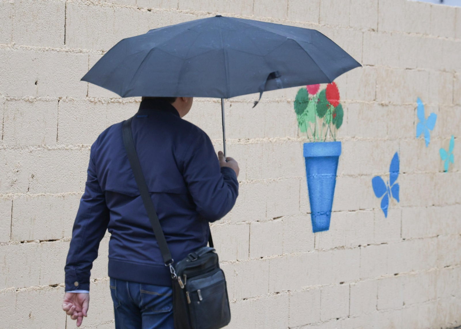 Un hombre se protege de la lluvia ne Málaga con un paraguas.