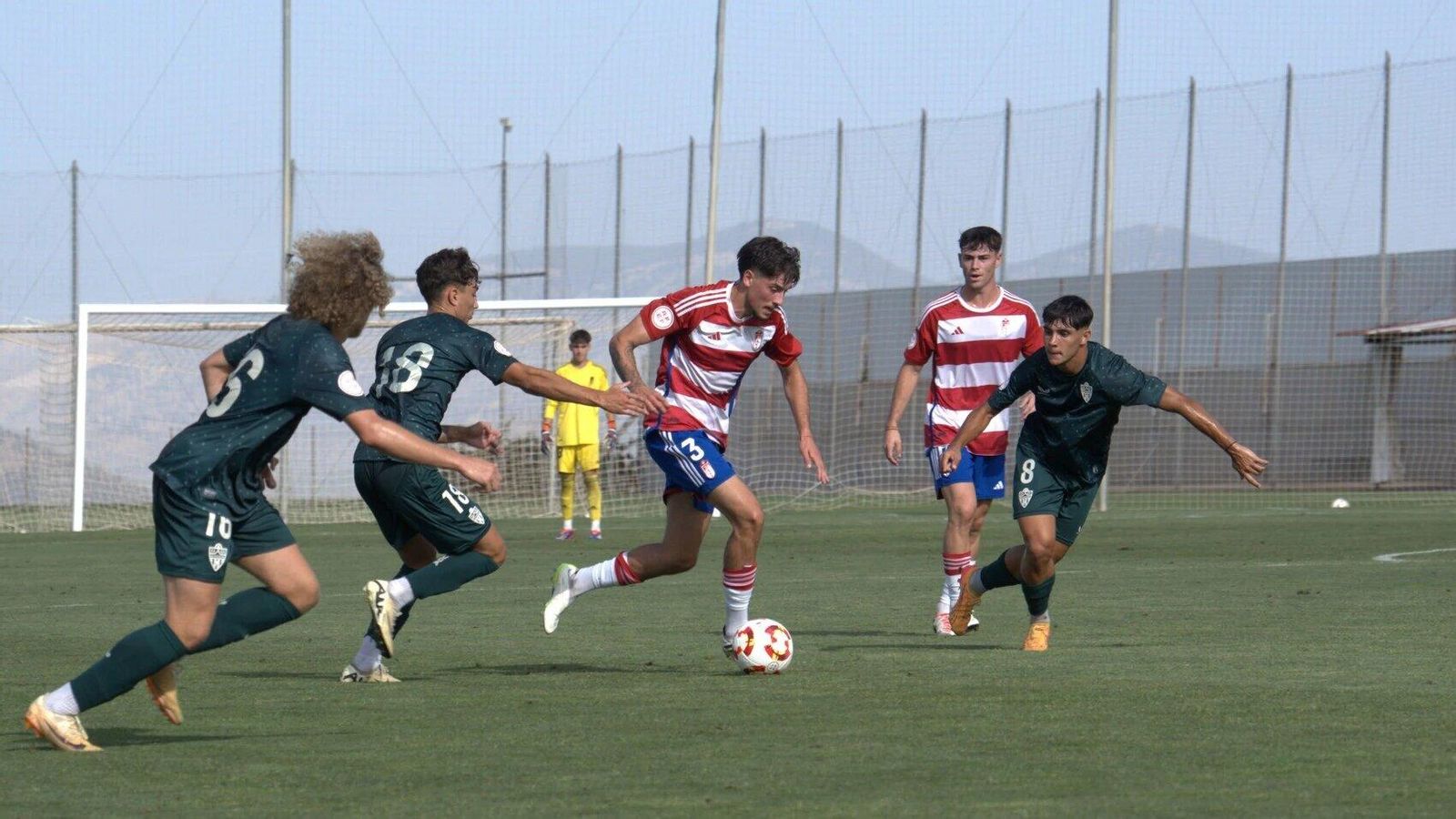 Hasta tres jugadores del conjunto almeriense presionan a un futbolista nazarí para intentaar robarle el balón.