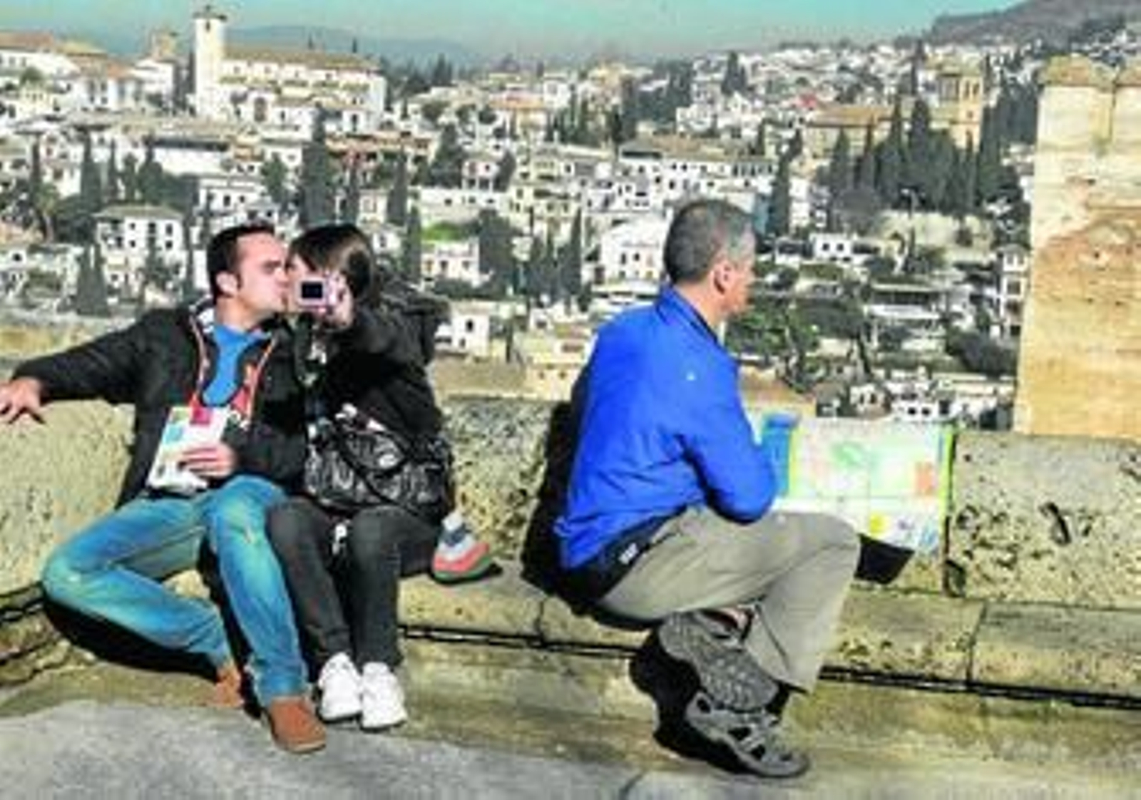 Unos turistas se fotografían en uno de los miradores del conjunto de la Alhambra, con el barrio del Albaicín al fondo.