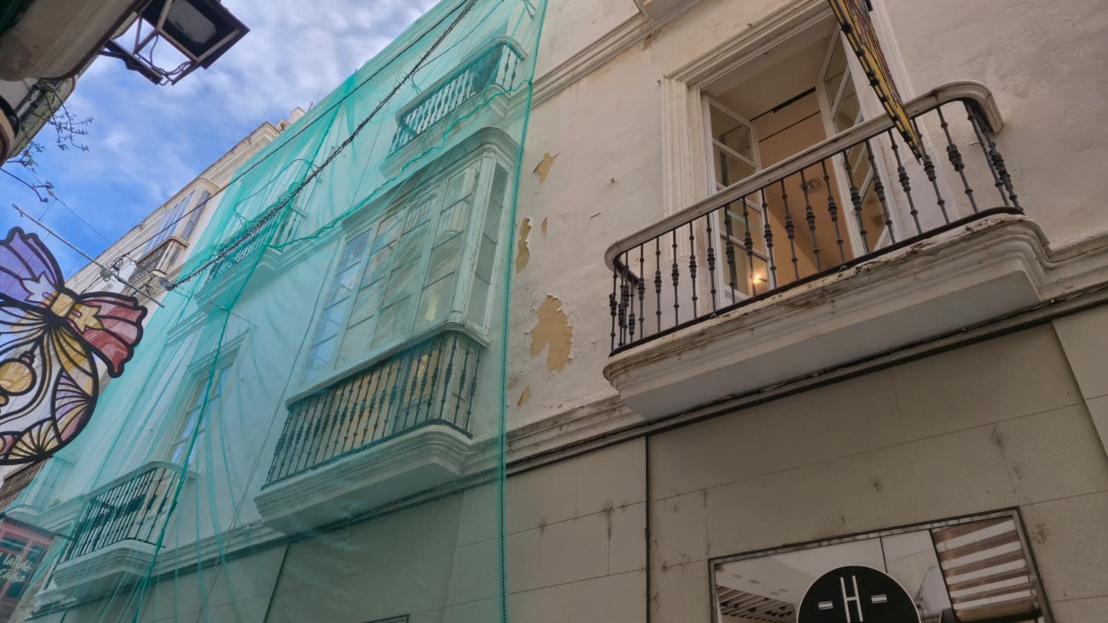 Una malla protege parte de la fachada del antiguo local de Zara en la calle Columela de Cádiz.