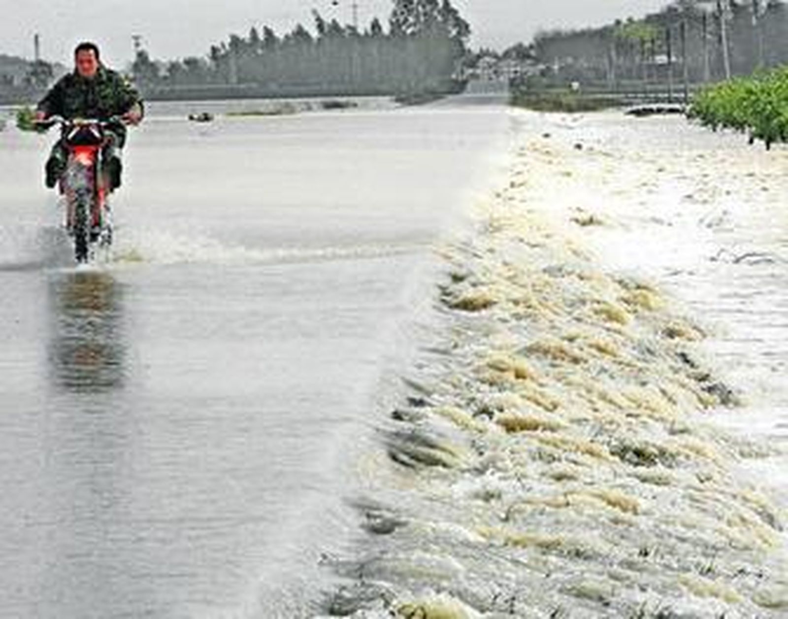 Un motoristas circula a duras penas sobre el gran charco en el que se ha convertido la carretera de La Ina tras las últimas lluvias torrenciales.