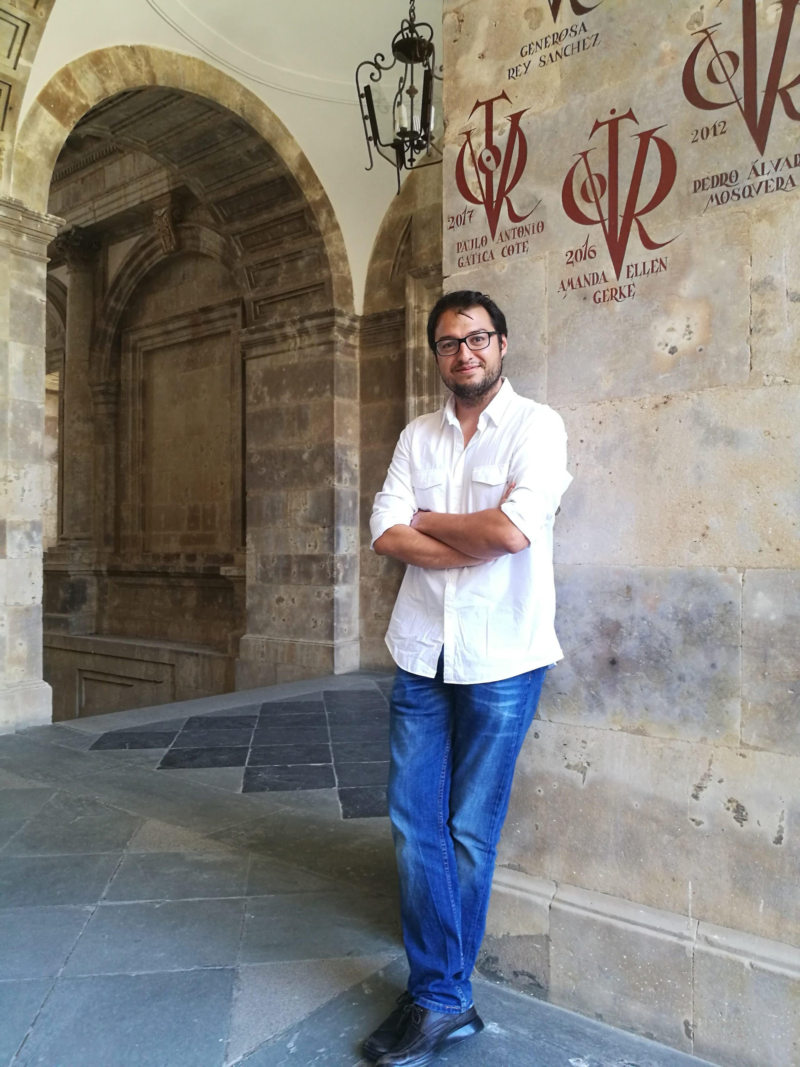Paulo Antonio Gatica, en el Palacio de Anaya (sede de la Facultad de Filología de la Universidad de Salamanca), bajo su vítor que lo acredita como doctor por dicha institución.