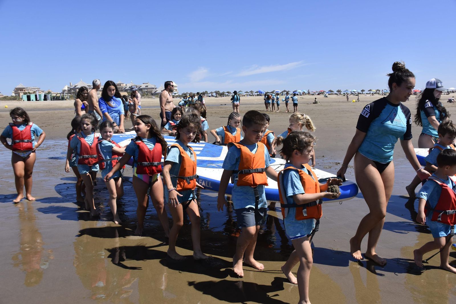 Niños y niñas de todas las edades se divierten practicando deportes acuáticos.