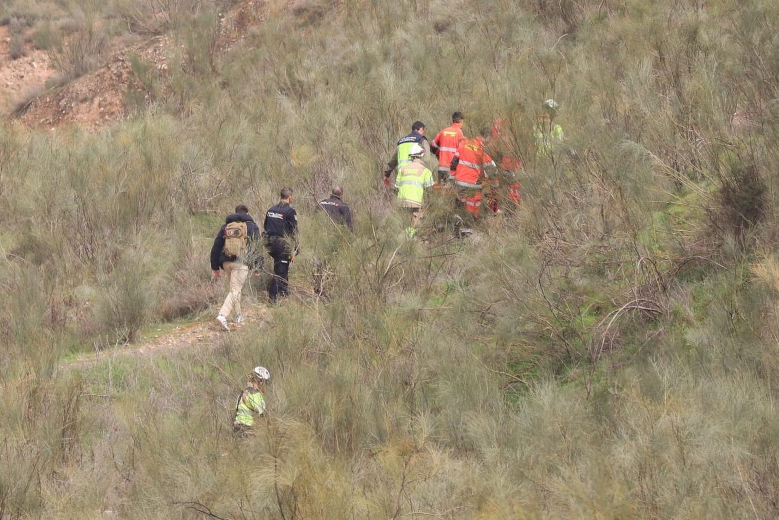 Agentes de Homicidios de la Guardia Civil y Bomberos transportan el cadáver desde la zona en la que ha aparecido cerca del Campus de Cartuja