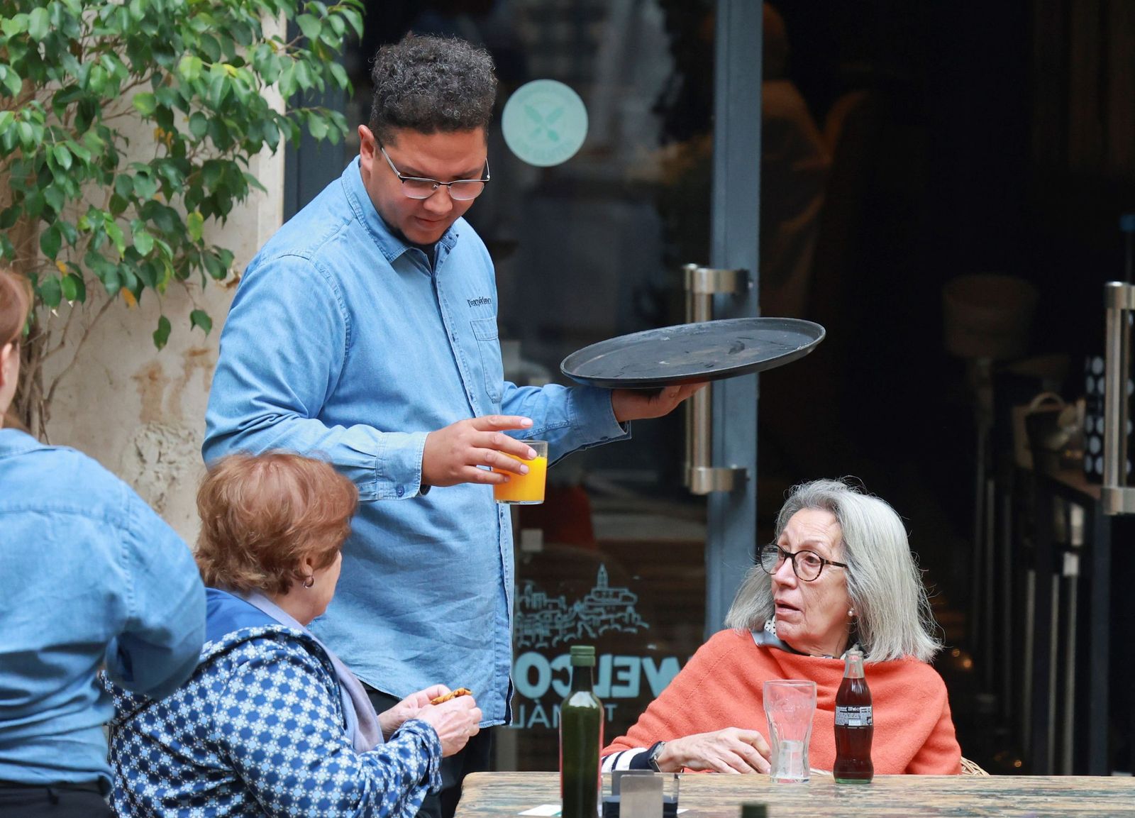 Un camarero trabajando en una terraza con dos clientas.