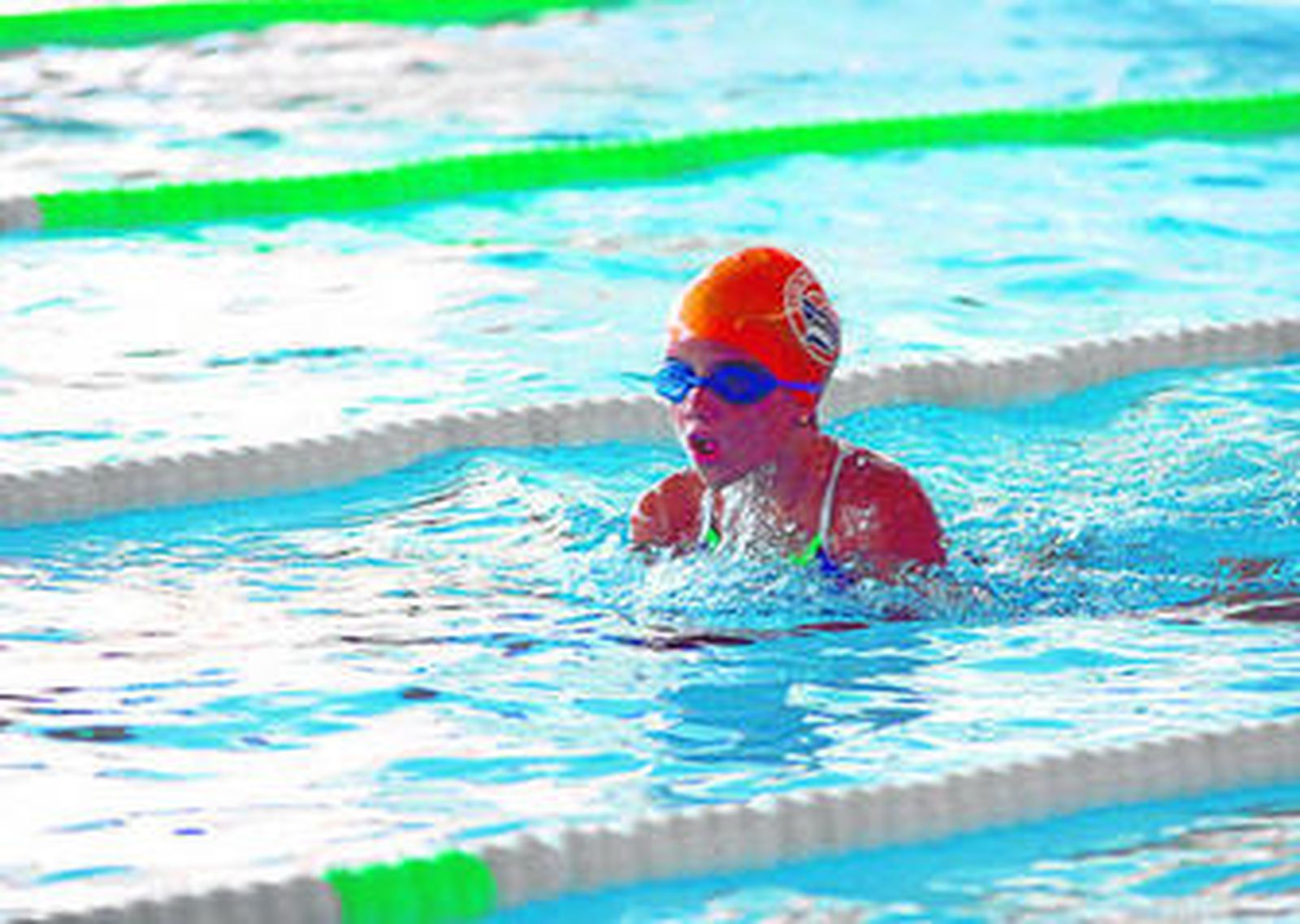 Una nadadora con gorro y gafas, en plena acción.