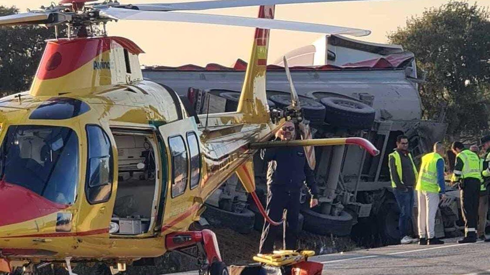 El helicóptero de emergencias, con el camión volcado de fondo.