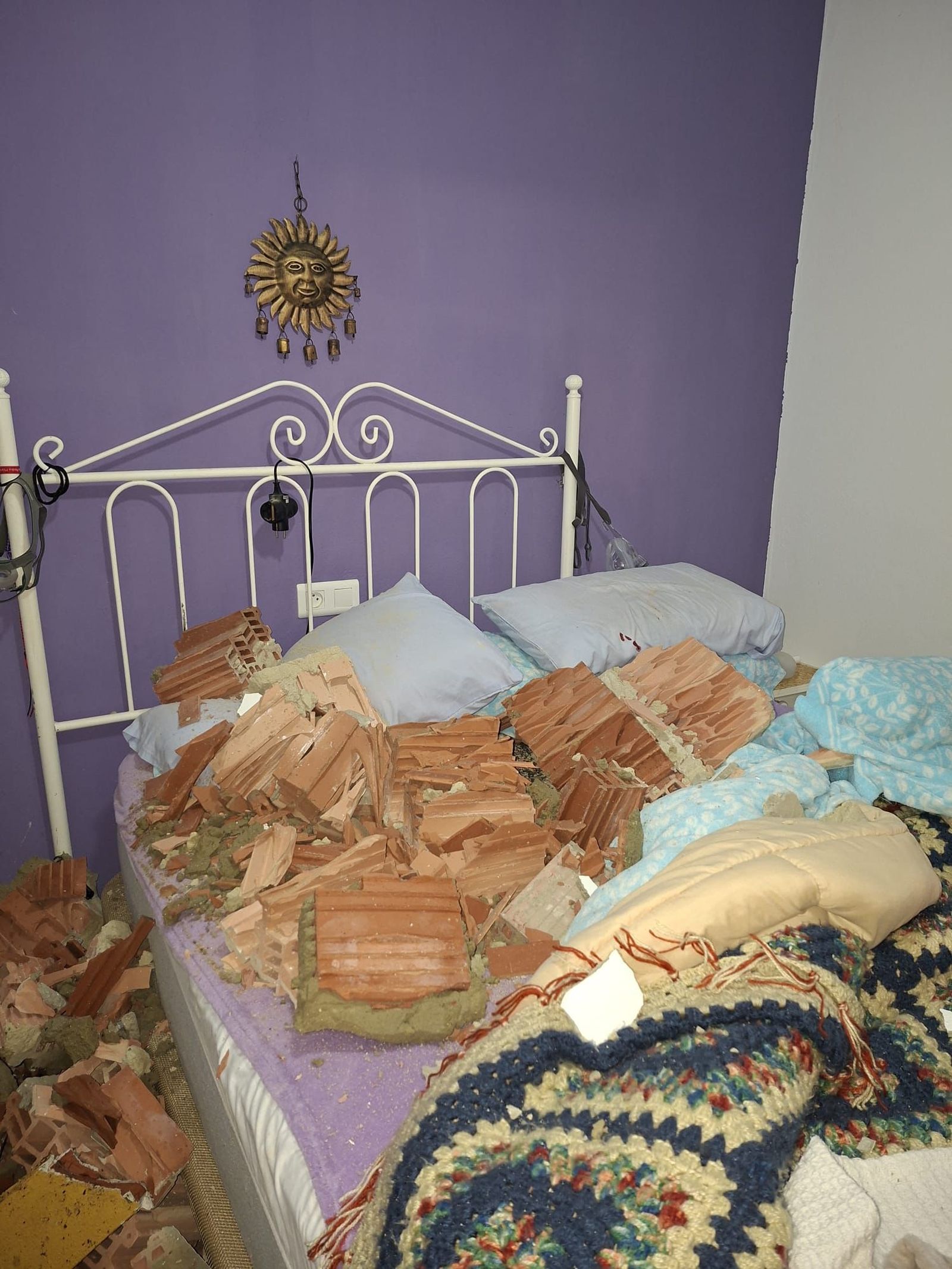 La cama en la que dormía el matrimonio, llena de cascotes tras derrumbarse el muro de hormigón sobre la vivienda.