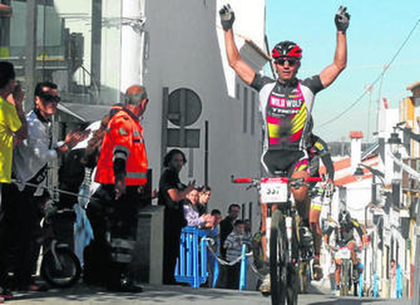 Trujillo levanta los brazos justo antes de cruzar la línea de meta; abajo, el campeón junto a los hermanos Macías.