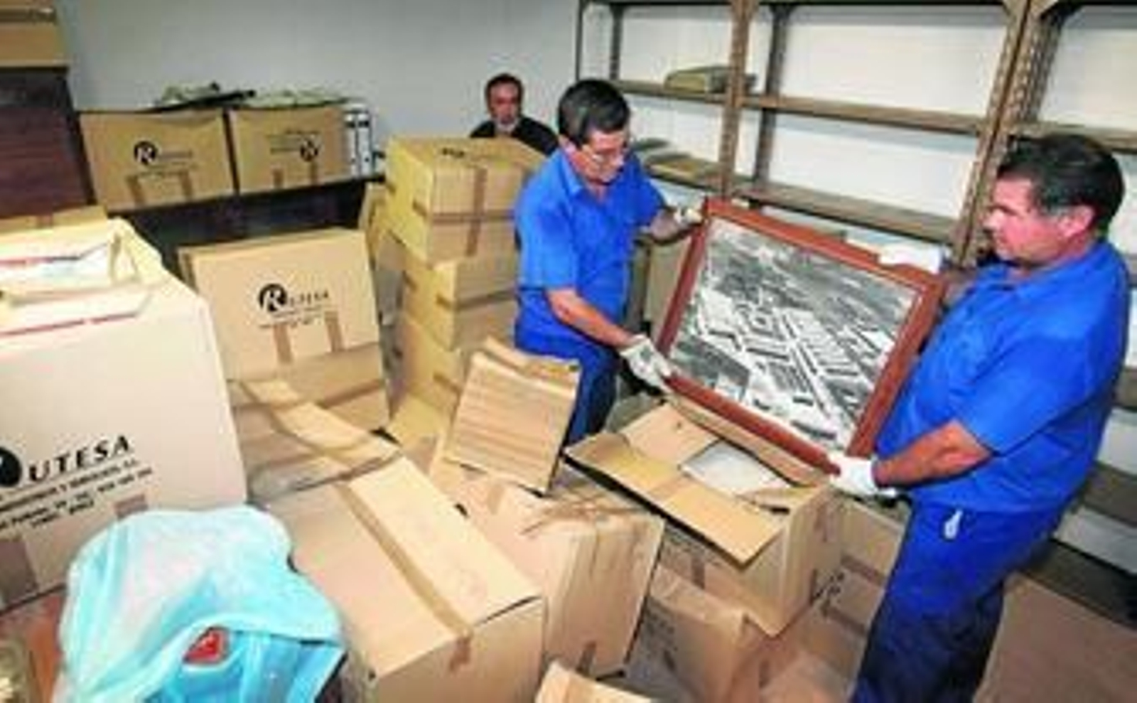 Operarios municipales hacen limpieza en los sótanos del Ayuntamiento a la búsqueda del Pendón y muestran una fotografía antigua de La Vid, ayer.