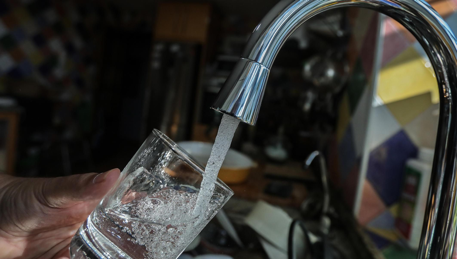 Una persona lleva un vaso de agua en el grifo. Una persona lleva un vaso de agua en el grifo.