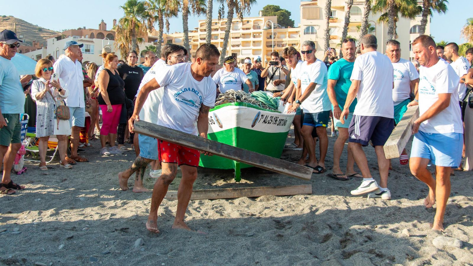 Van colocando los listones de madera para desplazar la barca hasta el mar