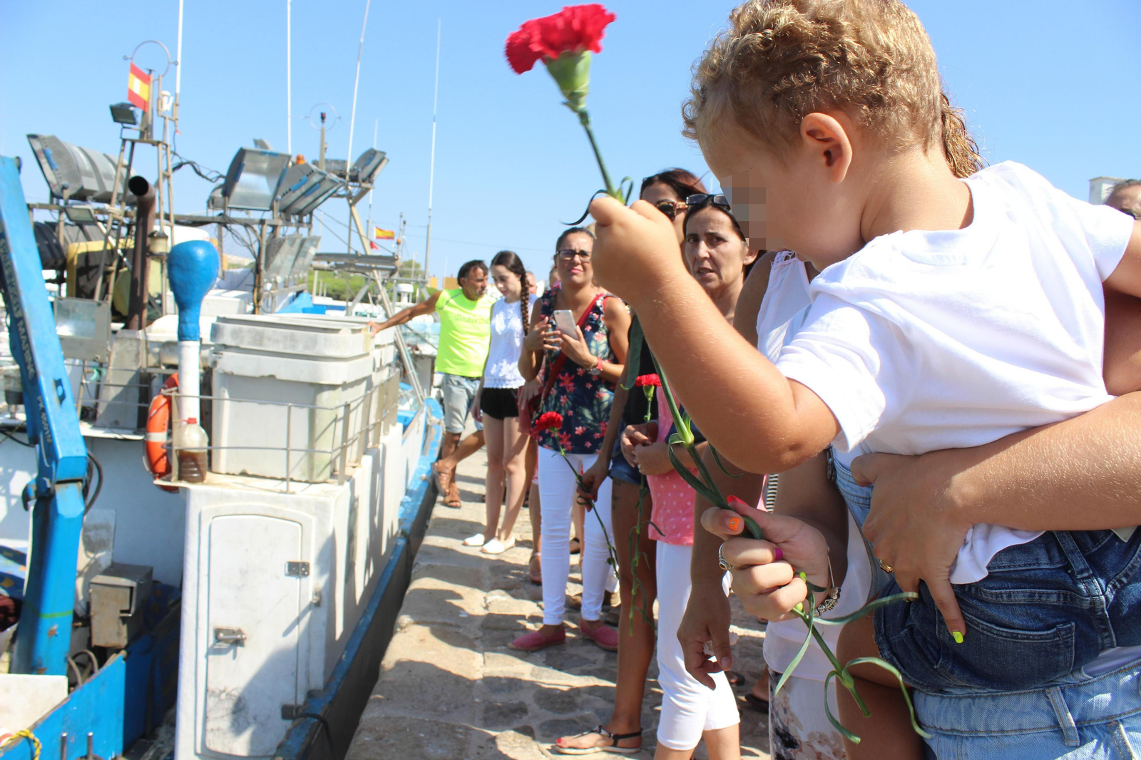 Familiares de los marineros fallecidos lanzaron claveles rojos a las aguas del puerto pesquero de La Albufera.