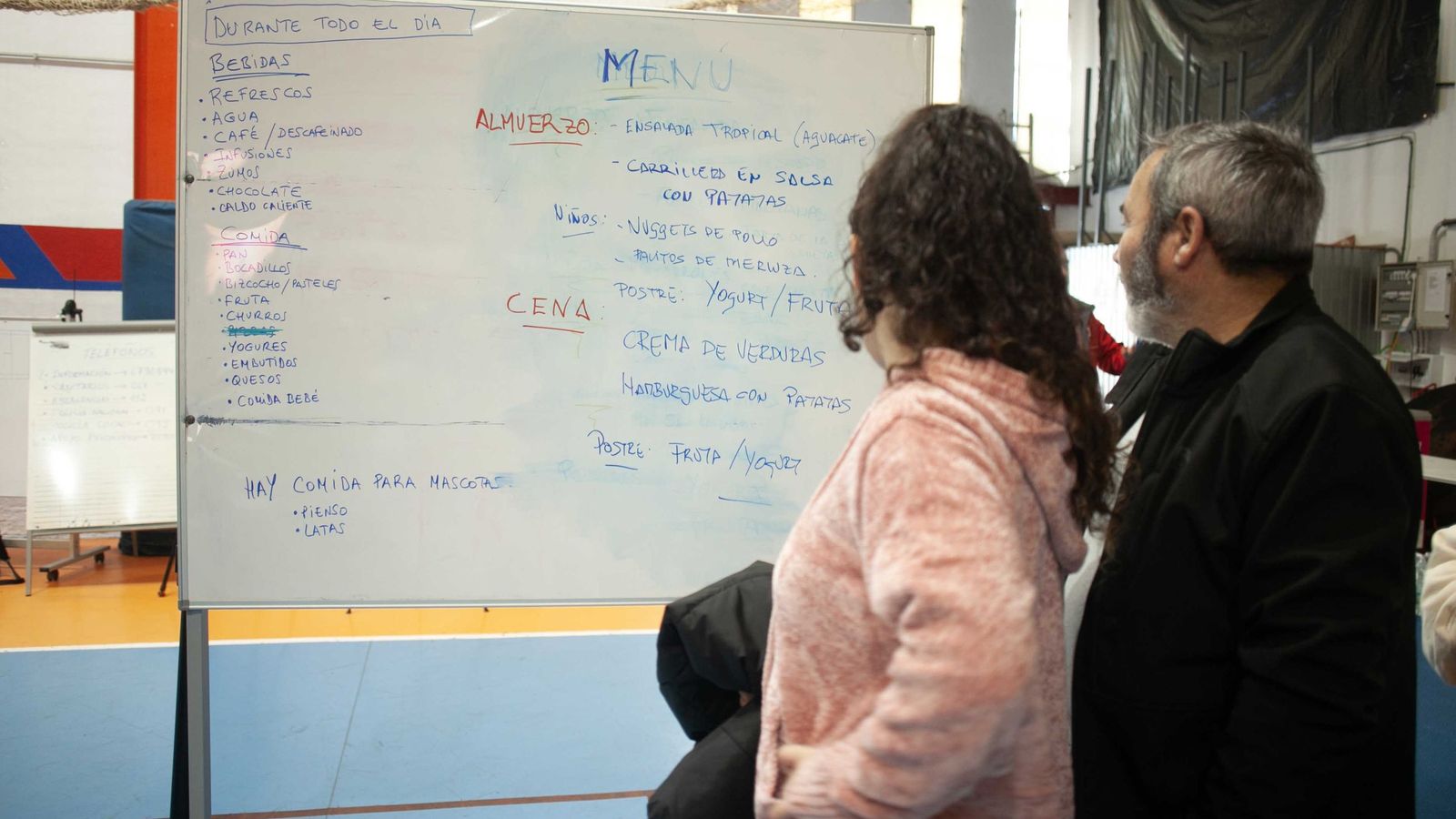 Desalojados observando la pizarra de comidas