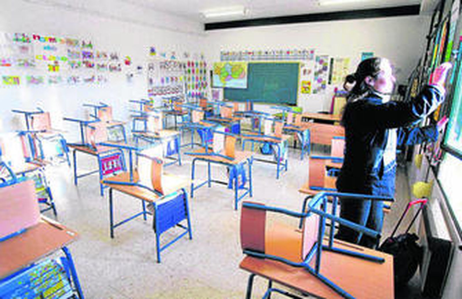 Una profesora cierra la ventana de su clase al terminar la jornada escolar.