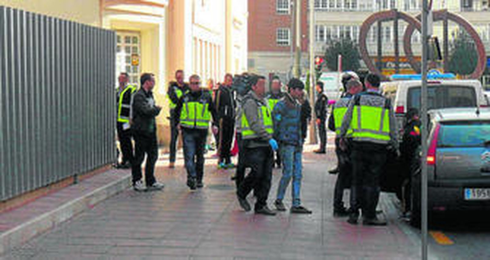 Dos agentes de la Policía Nacional trasladan a uno de los detenidos a dependencias policiales.