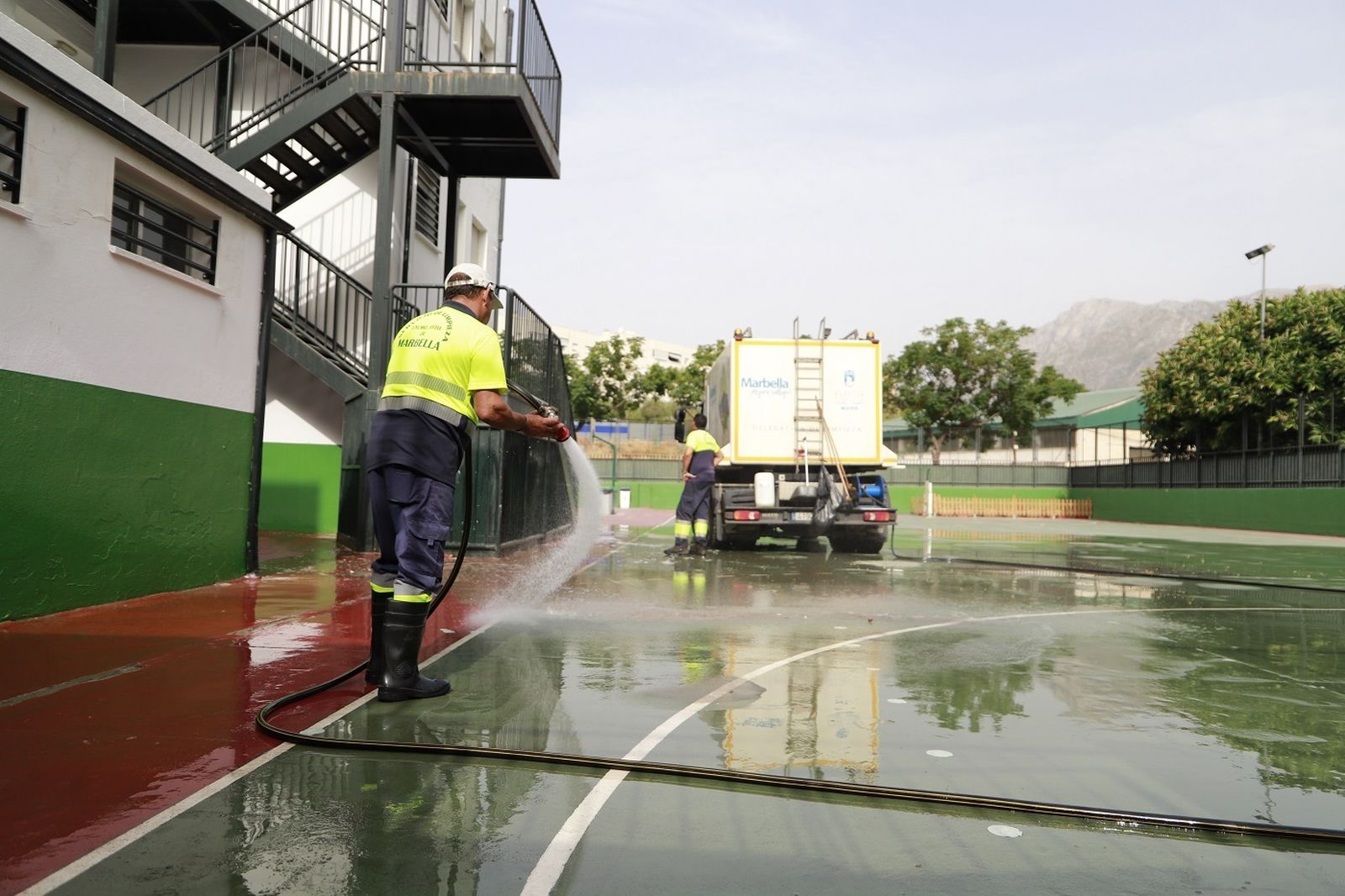 Un operario realizando labores de limpieza en el patio de un colegio de Marbella.