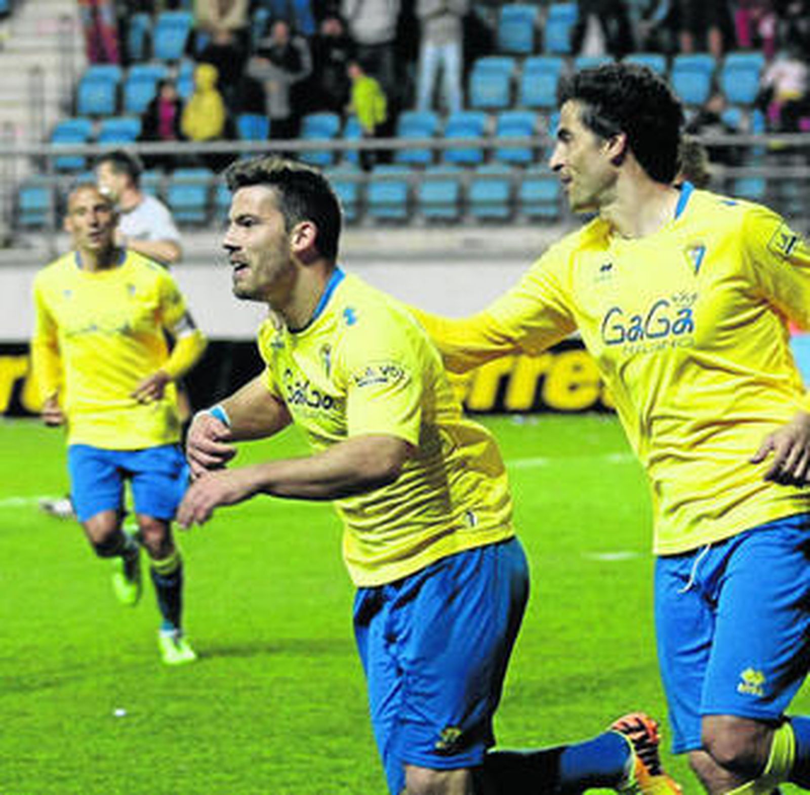 Jorge Luque (al fondo) corre hacia Kike López y Jorge López (d) para celebrar un gol.