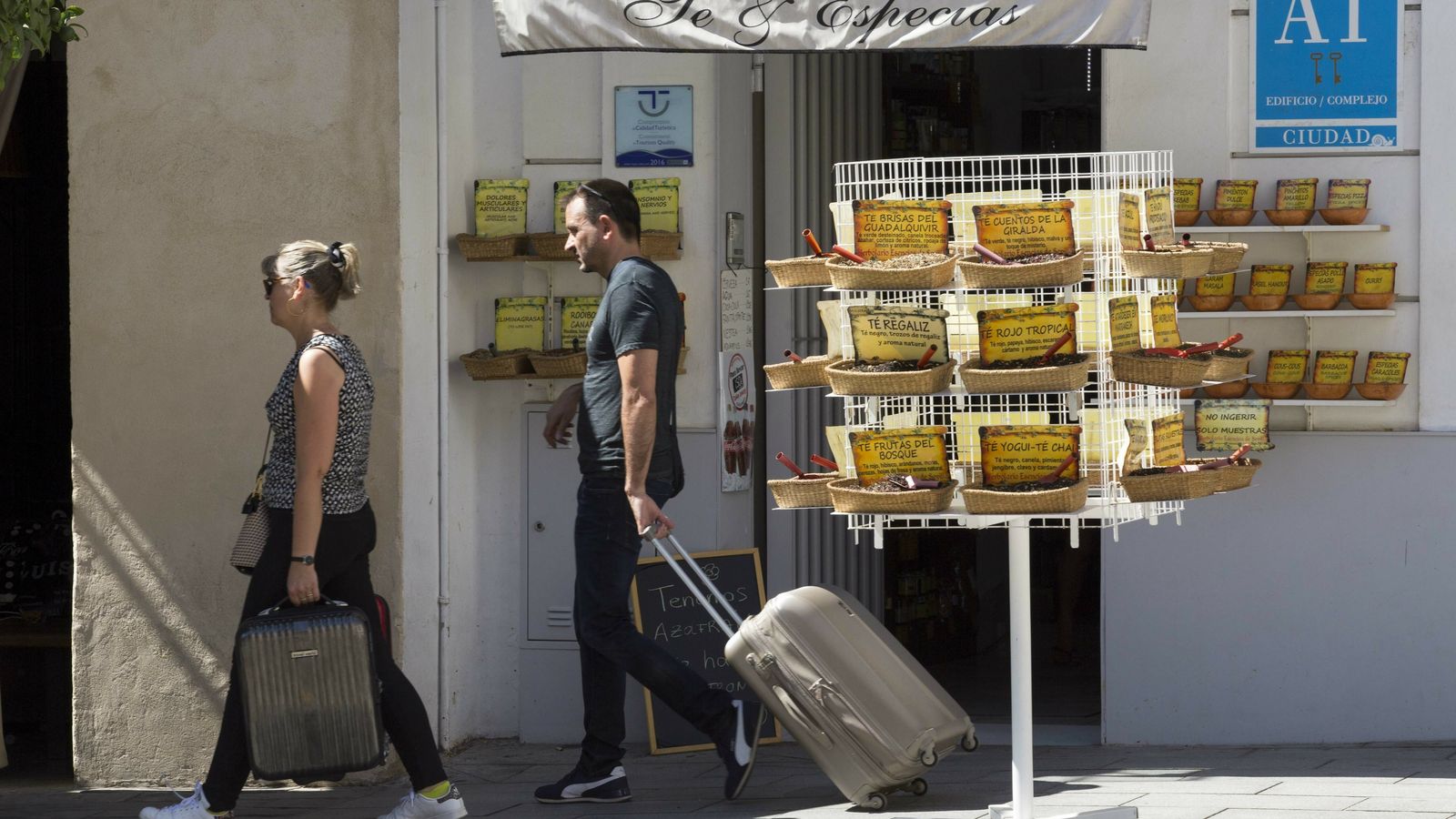 Dos turistas pasan junto a un edificio de apartamentos turísticos.