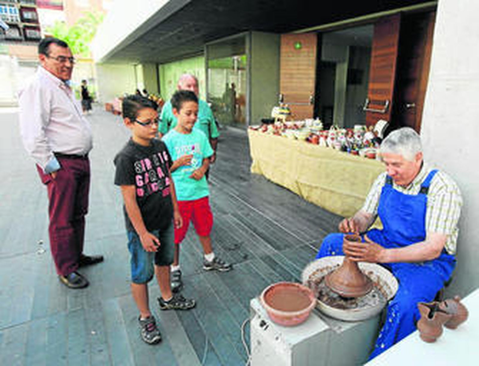 Juan Alfonso, El Puntas, trabajando a las puertas del Museo mientras dos jóvenes lo observan.