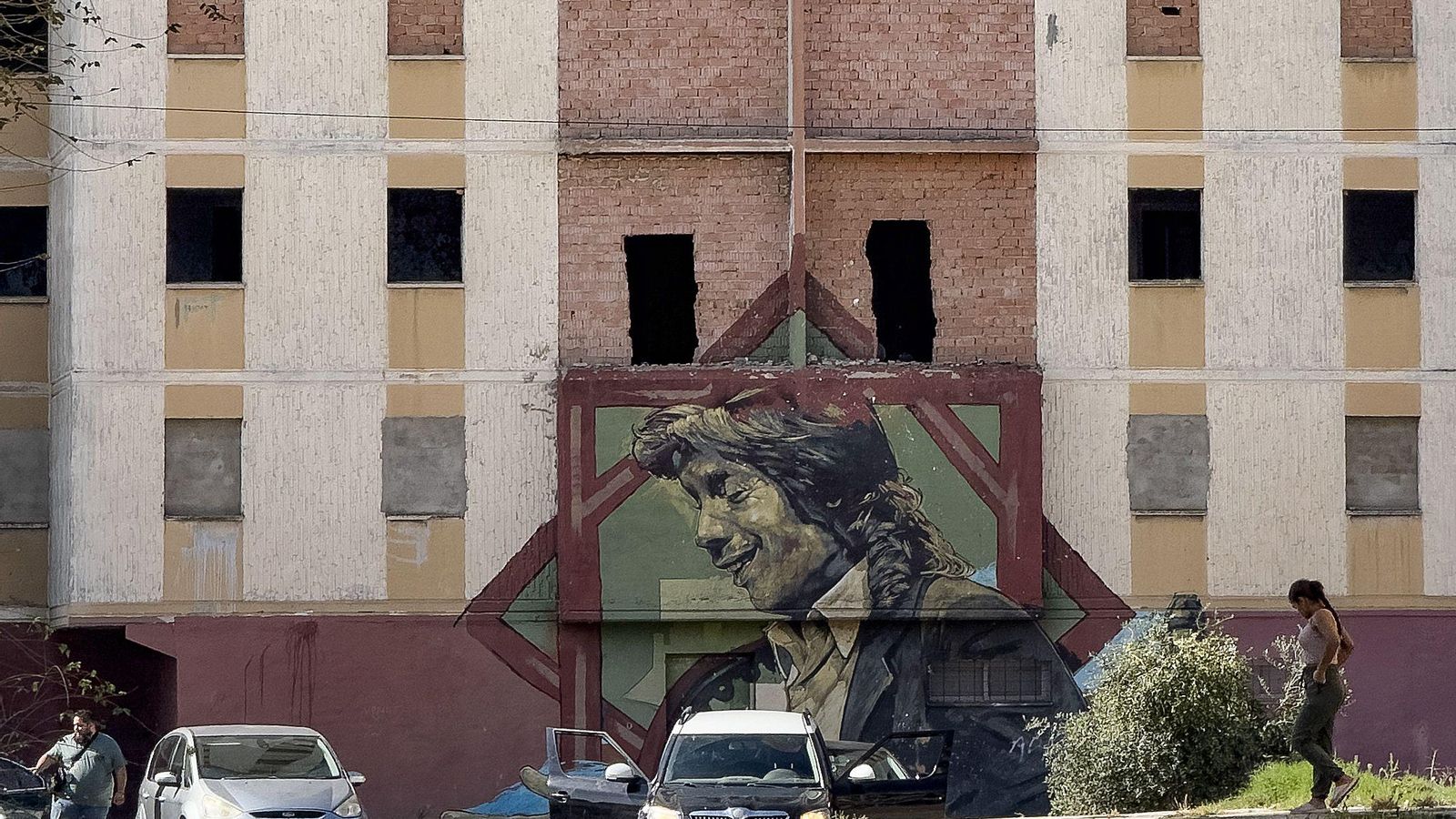 Varios vecinos pasan por delante del grafiti dedicado a Camarón en el Polígono Sur.