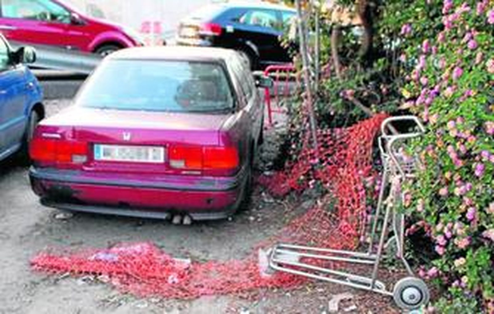 Imagen de un coche abandonado en las inmediaciones del aeropuerto junto a un carro 'portamaletas'.