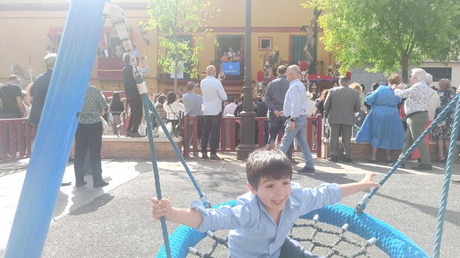 Un niño juega en el parque infantil del Pumarejo mientras pasa el Cristo de la Buena Muerte.