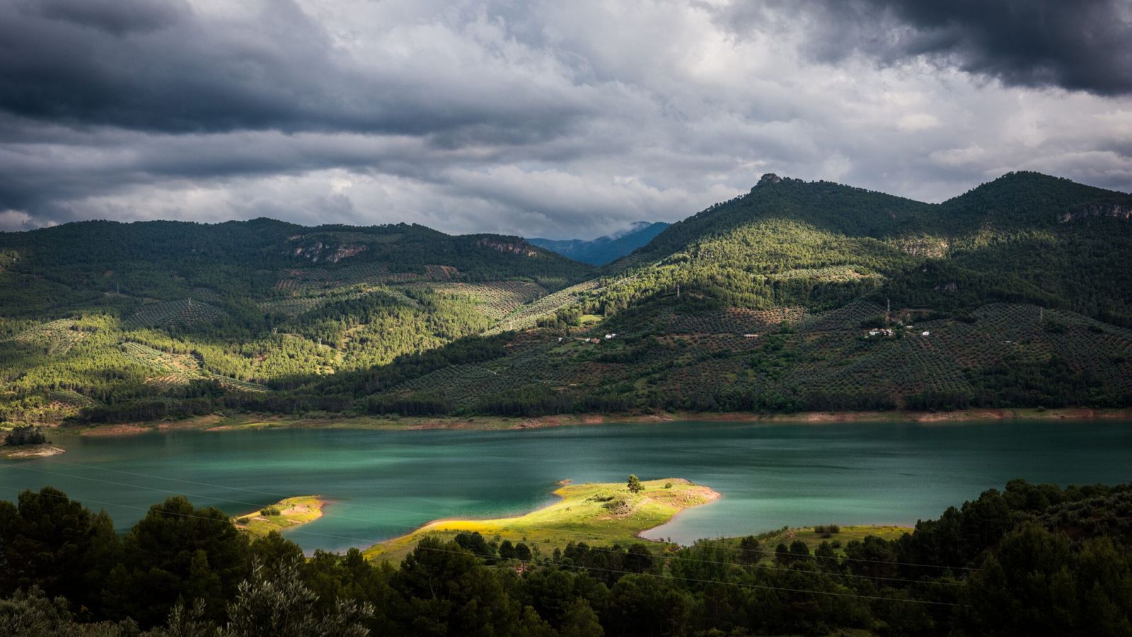 Panorámica del Embalse del Tranco, uno de los paisajes más icónicos de la Sierra de Segura, con las montañas cubiertas de pinar reflejándose en sus aguas turquesas, un entorno privilegiado para las actividades de naturaleza propuestas en la zona.