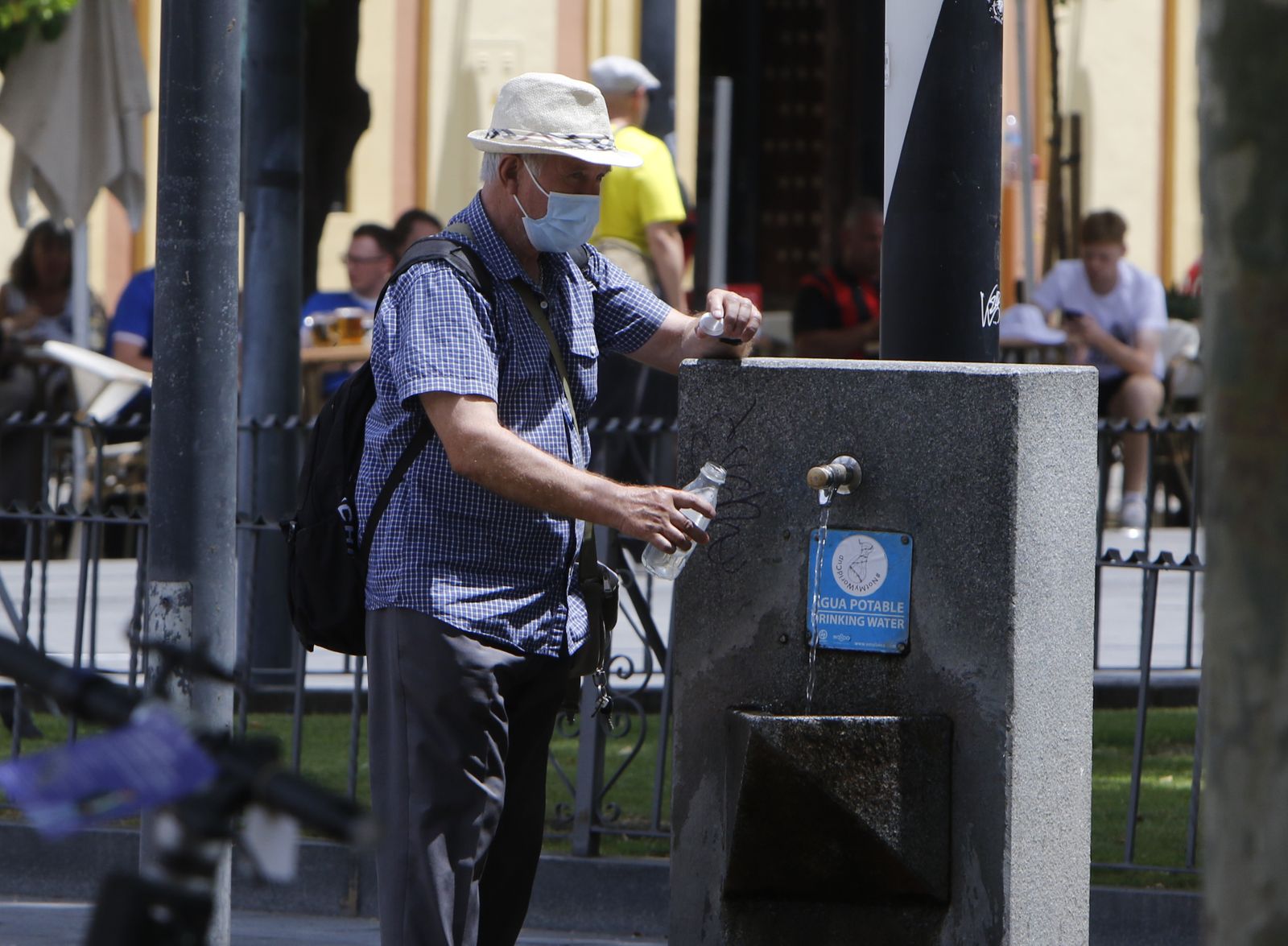 Un hombre coge agua de una fuente.