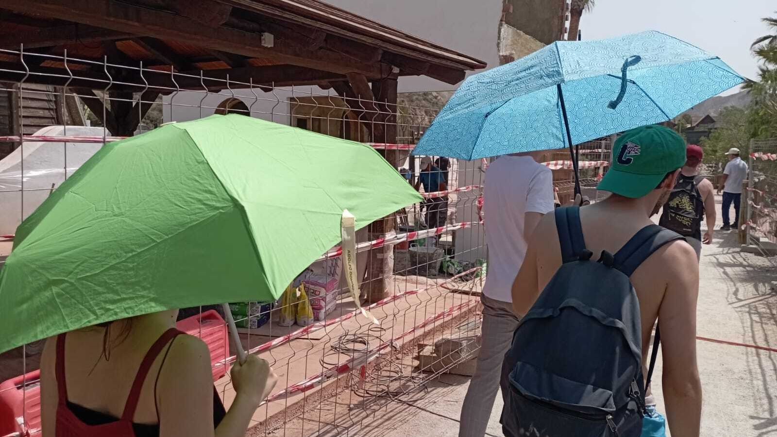 Un paraguas como refugio de los turistas que esperan bajo un  sol de justicia en la cola del acceso al Minihollywood.