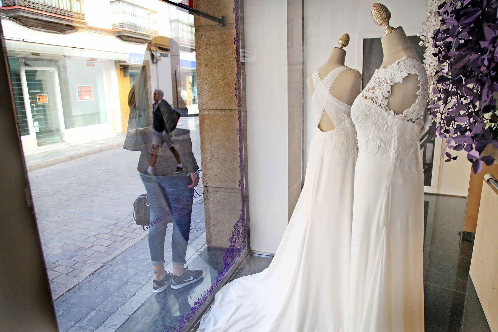 Una mujer mira vestidos de novia en un escaparate.