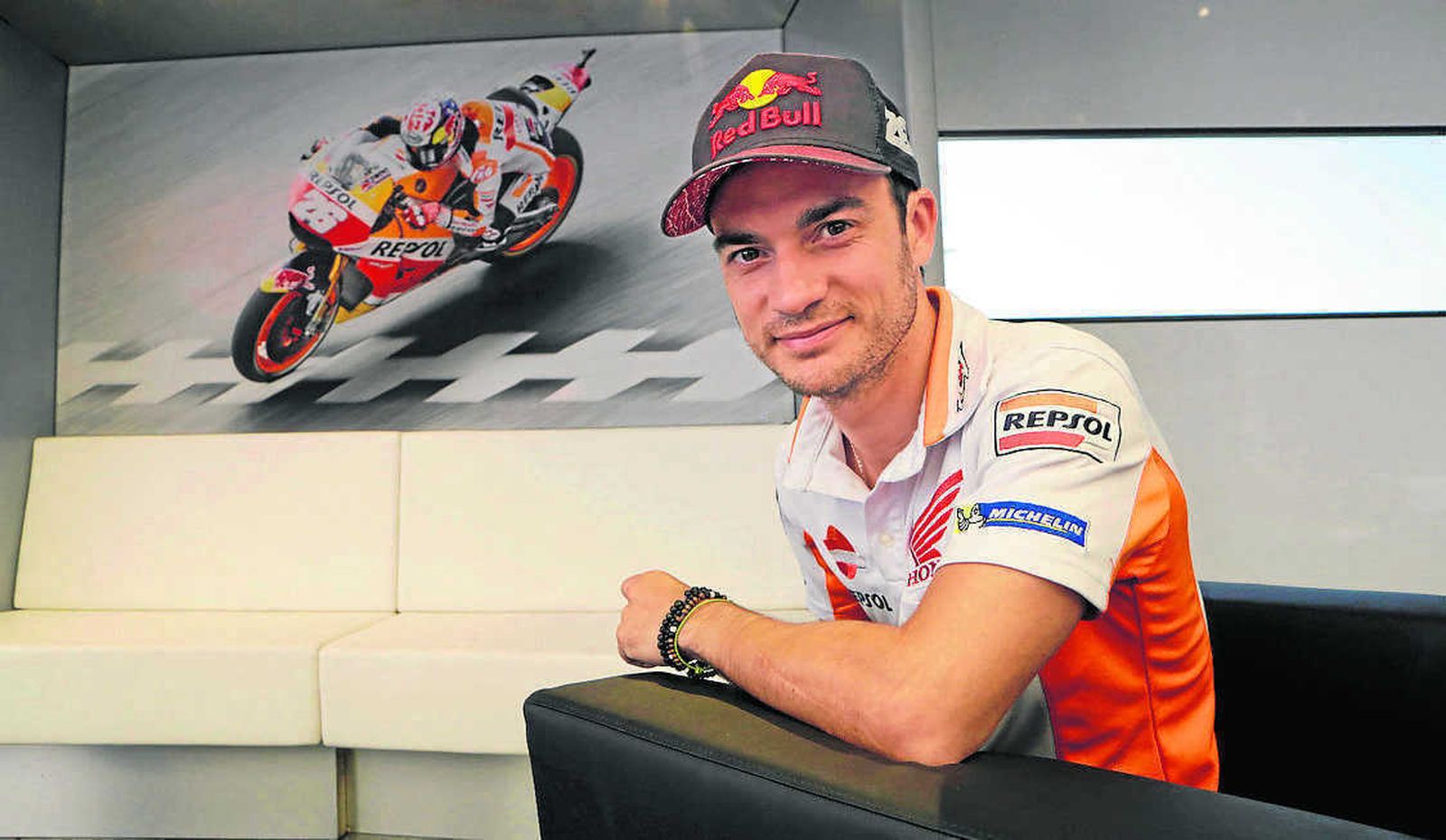 Dani Pedrosa posa junto a un cartel con una fotografía suya en acción.