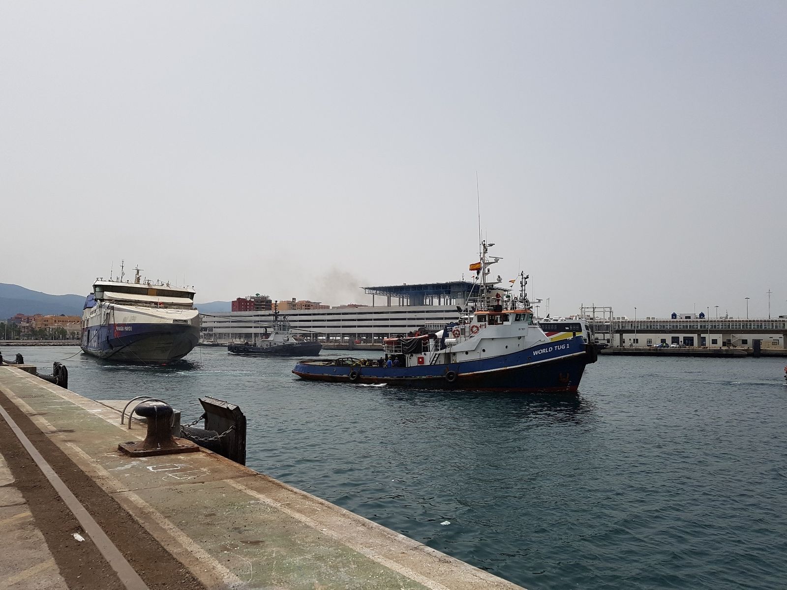 El remolcador 'World Tug I' saca al ferry del atraque del muelle de Isla Verde.