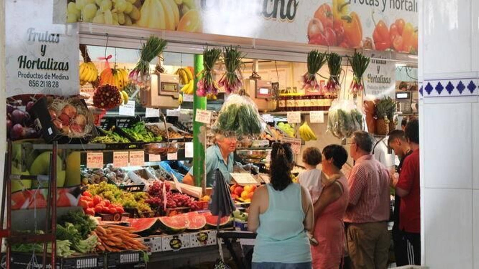 Una mujer atiende a clientes en un puesto de frutas