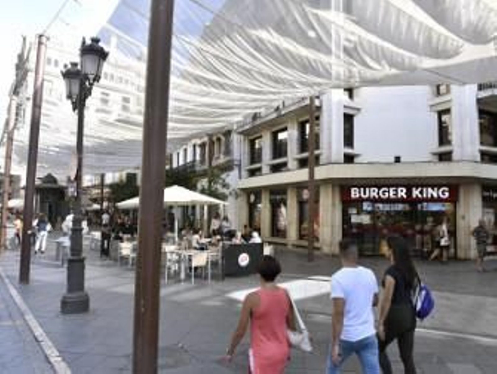 Sevillanos y foráneos caminan sorteando veladores por la Campana. / Juan Carlos Vázquez