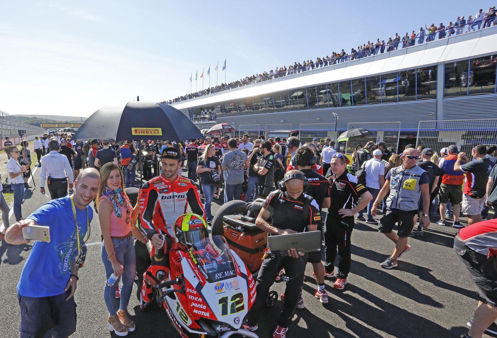 Un aficionado se hace una foto con el español Xavi Forés momentos antes de la salida de la carrera de Superbikes.