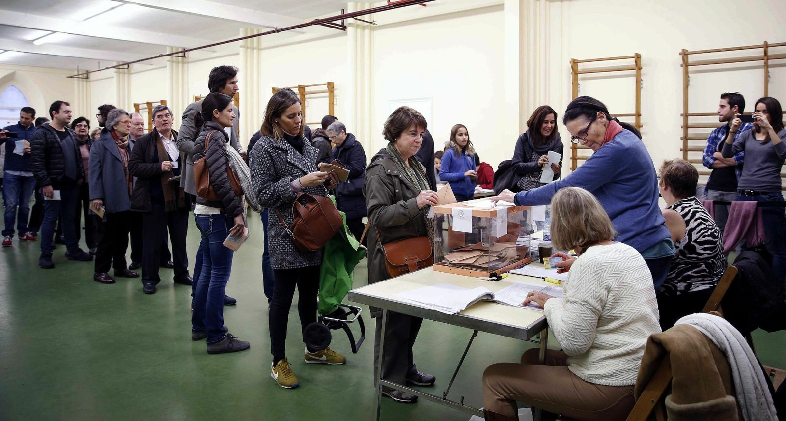 Numerosas personas esperando para votar en un colegio