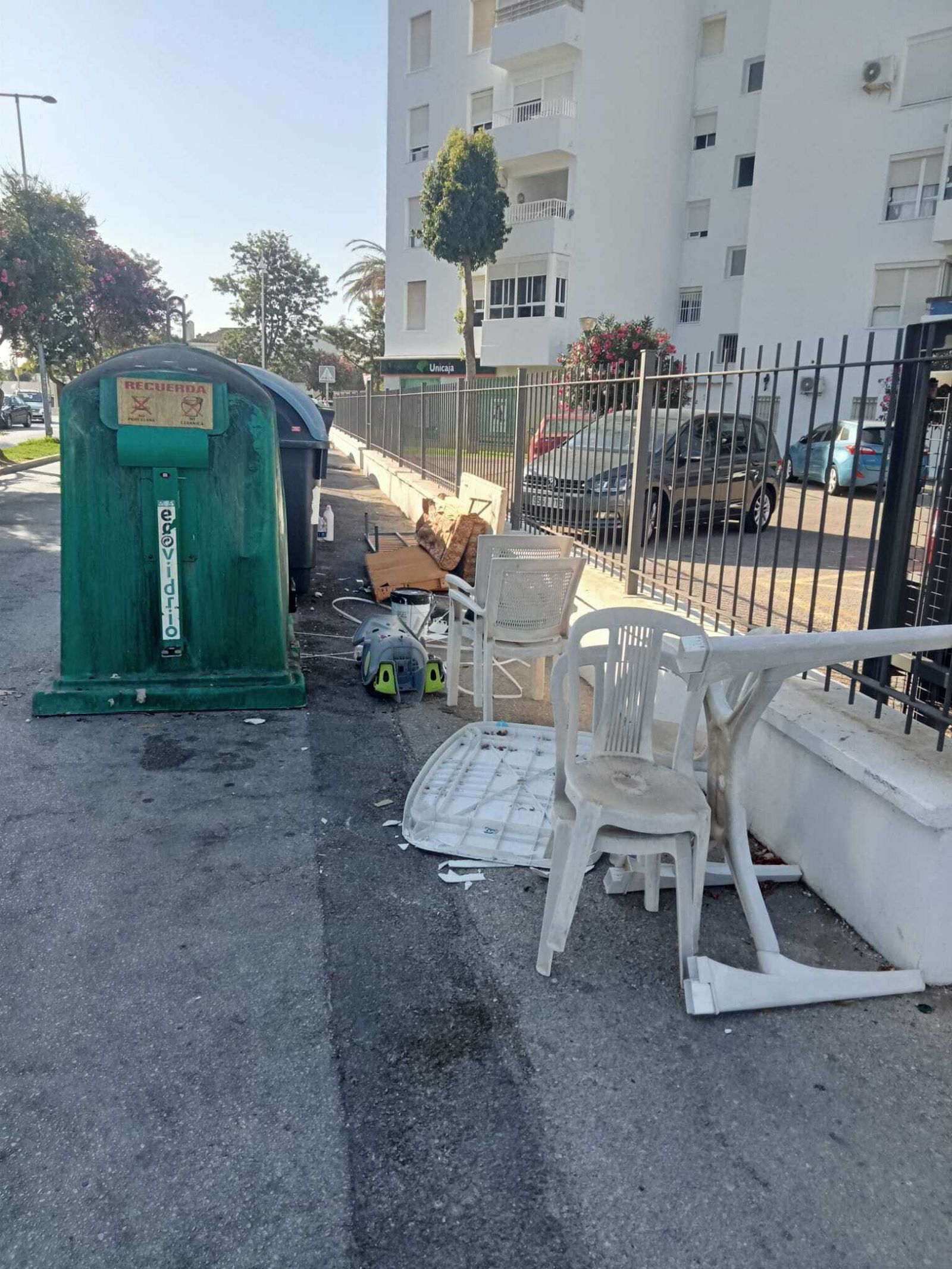 Suciedad y enseres abandonados en una isleta de contenedores.