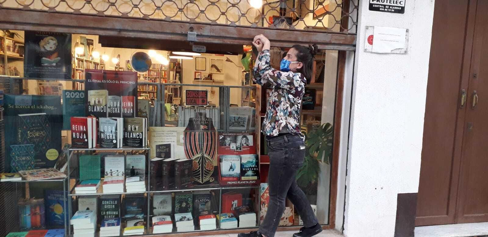 La propietaria de la Librería Zorba, echando la persiana  a las seis de la tarde.