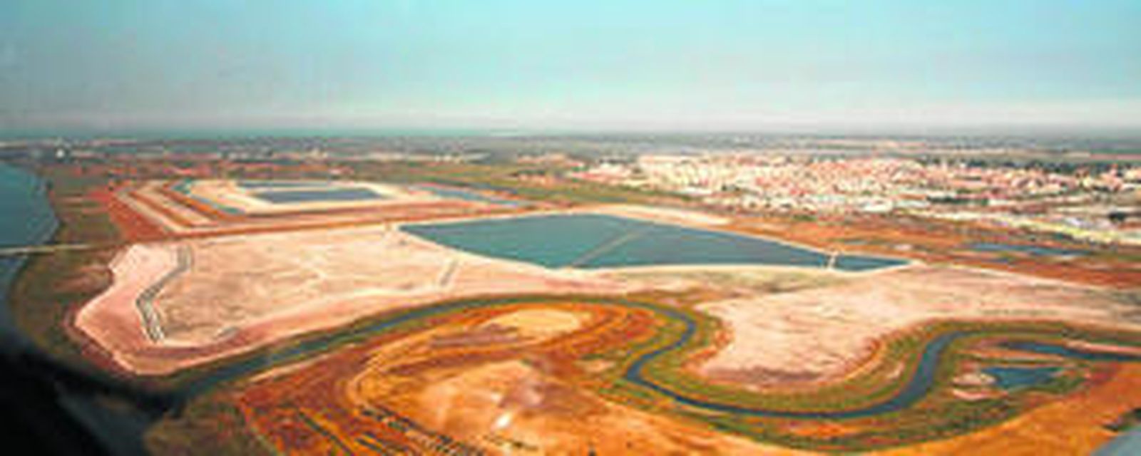 Vista aérea de las balsas de fosfoyeso con la ciudad al fondo.