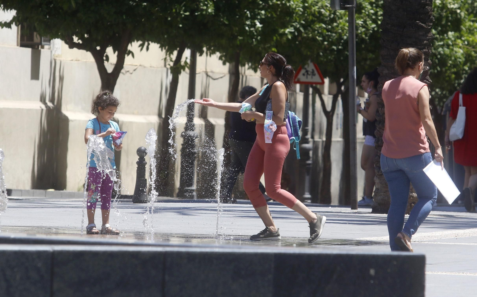 Una mujer se refresca en el fuente de las Tendillas.
